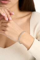Silver tone double row crystal bangle on the wrist, hand at chin