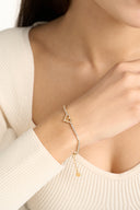 Woman wearing gold CZ heart tennis bracelet on wrist — AURA Jewelry