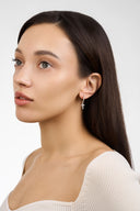Model wearing dainty crystal cross huggie earring with pave CZ cross charm in silver tone - AURA Jewelry