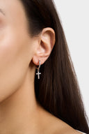 Close up of pave crystal cross huggie earring with sparkling CZ cross charm worn on ear - AURA Jewelry