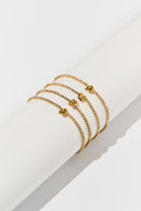 Gold initial bracelet with sparkling tennis style chain and alphabet letter charm, shown as a dainty personalized bracelet for her. Minimalist letter bracelet jewelry designed as an everyday gold bracelet, birthday gift, bridesmaid gift, and custom alphabet bracelet with A to Z letter options.