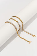 Baguette crystal tennis bracelets with toggle clasp draped over a white cylinder