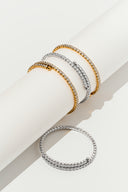 Gold tone and silver tone double row crystal bangles on a white cylinder