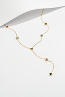 Gold tone Y necklace with multicolor heart stones next to a curl of white paper