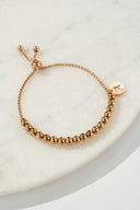 Silver beaded bolo bracelet with engraved letter M charm on beige background — AURA Jewelry