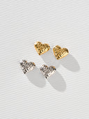 Textured heart stud earrings in gold and silver with a sculptural hammered finish, shown as minimalist heart earrings for women. Gold heart earrings and silver heart studs displayed as romantic gift jewelry, everyday stud earrings, and modern heart shaped earrings with a soft reflective surface.