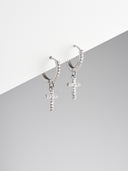 Pair of silver tone pave crystal cross huggie hoop earrings with CZ cross charm on grey background - AURA Jewelry