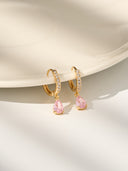 Gold birthstone huggie earrings with crystal huggie hoops and pear shaped gemstone drops arranged in several birth month color options. These dainty drop earrings are shown as elegant gift for her jewelry, birthday gift earrings, minimalist gold earrings, and personalized birth month earrings. Teardrop gemstone charm earrings with a refined everyday look, perfect for bridesmaid gifts, anniversary gifts, or stacking with other delicate jewelry pieces.

