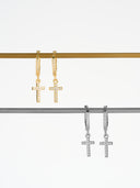 Gold and silver crystal cross huggie earrings with pave CZ cross charm displayed on metal rack - AURA Jewelry